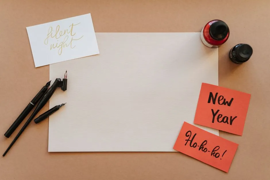 Fountain pens and ink bottles beside hand-lettered greeting cards on a desk.
